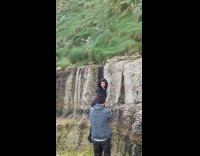 Woman in black outfit fierce pose on the rock