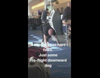 Man does yoga before his flight at a n airport terminal, downward dog