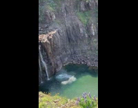 Guy jumps off of waterfall cliff into water 