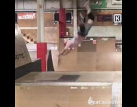 Guy backflips on scooter in indoor skatepark and lands on his stomach