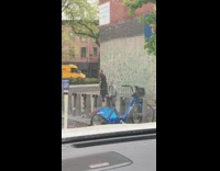 Man wearing yarmulke does a martial arts kick to wall on the sidewalk