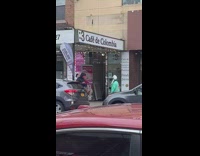 Man Wearing Turquoise Costume and White Wig Walks Past Stores 