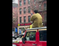Guy brown jacket sit on red jeep roof