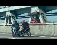 Man pushes another motorcycle at the bridge