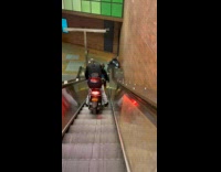 Collab Subway Creatures - Man loads motorcycle on subway escalator towards platform