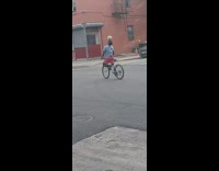 Man pink shorts ride bicycle with a ball on head