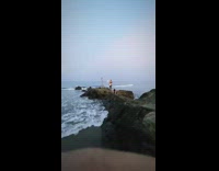 Girl fire dances brown rocks ocean water