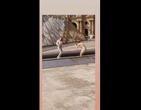 Woman in white crop top dances in front of the Louvre
