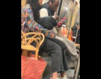 Man long pink nails uses phone on subway