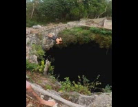 Shirtless guy jumps through sinkhole into water