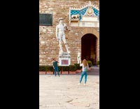 Guy copies statue pose brown building girl