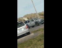 Car with surfboard sticking out of sunroof 