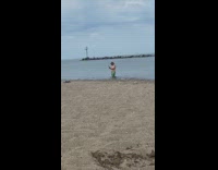 Man shirtless films toy hotdog beach waves