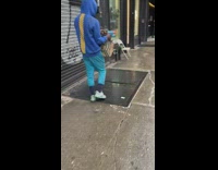 Guy in hoodie walking on sidewalk with a nerf gun 
