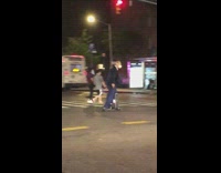 Guy in business attire skateboards with sticks and suitcase 