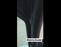 Person driving dune buggy through sand dunes