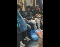 Guy holds newborn kitten in palm of his hand and feeds it milk out of bottle