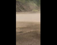 Red car drives down mountain road dirt