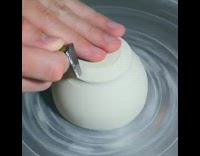 guy molding spinning white clay with medal tool