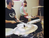 Dad daughter play drums pink headphones indoors