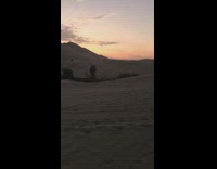 Camera crew films girl dance desert dress