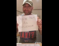 Grey shirt guy holds handwritten signs influencer 