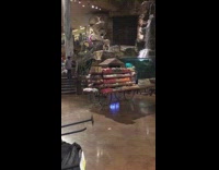 man in pink jumps into fish tank next to waterfall