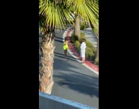 Tan lady in body con dress films with ring light on street 