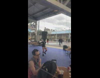 Guy balancing a trash can on top of head while dancing at the park 
