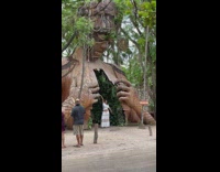 Woman white dress raises hand in front of the Tulum Statue