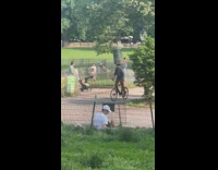 Guy rides bike with trash can on his head