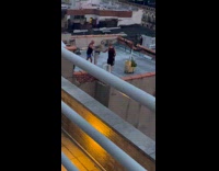 Two bald men dancing on roof next to grill