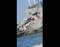 Woman large bikini orange top blue flag beach rocks