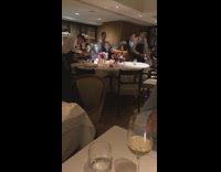 People at restaurant table waiter holds phone 