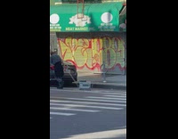 Bald guy dragging two radiator looking devices on the street