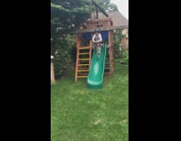 Boy rides razor scooter down green playground slide and falls on grass