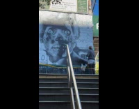 Woman paint wall top of subway stairs
