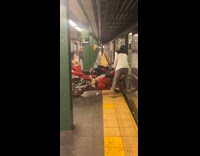 Two guys push red motorcycle onto subway 