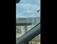 Guy on porch waving large stick with trash bag on it around