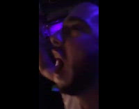 Guy pats bar stools while looking at people dancing on bar top 