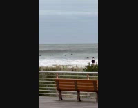 Surfers ride the large wave on beach