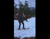 Guy tries to snowboard down small slope on wooden plank and falls off