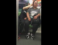 Woman adidas shirt picks friends ear with pinky finger on subway train