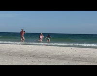 Three women walk beach stumble down water