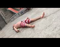 Drunk guy lays on the floor next to swimming pool with beer can in hand
