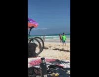 IITW - man i red swim shorts takes womans beach picture