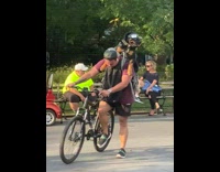 Man ride bike large dog in backpack