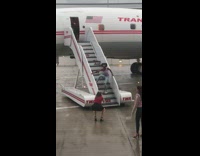 Woman violet top poses on airplane stairs on the runway