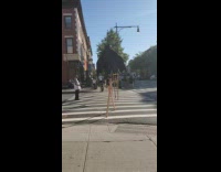 Bat costume and kids walks on tall wooden stilts down sidewalk