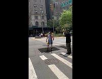 Shirtless man talks to performer on street